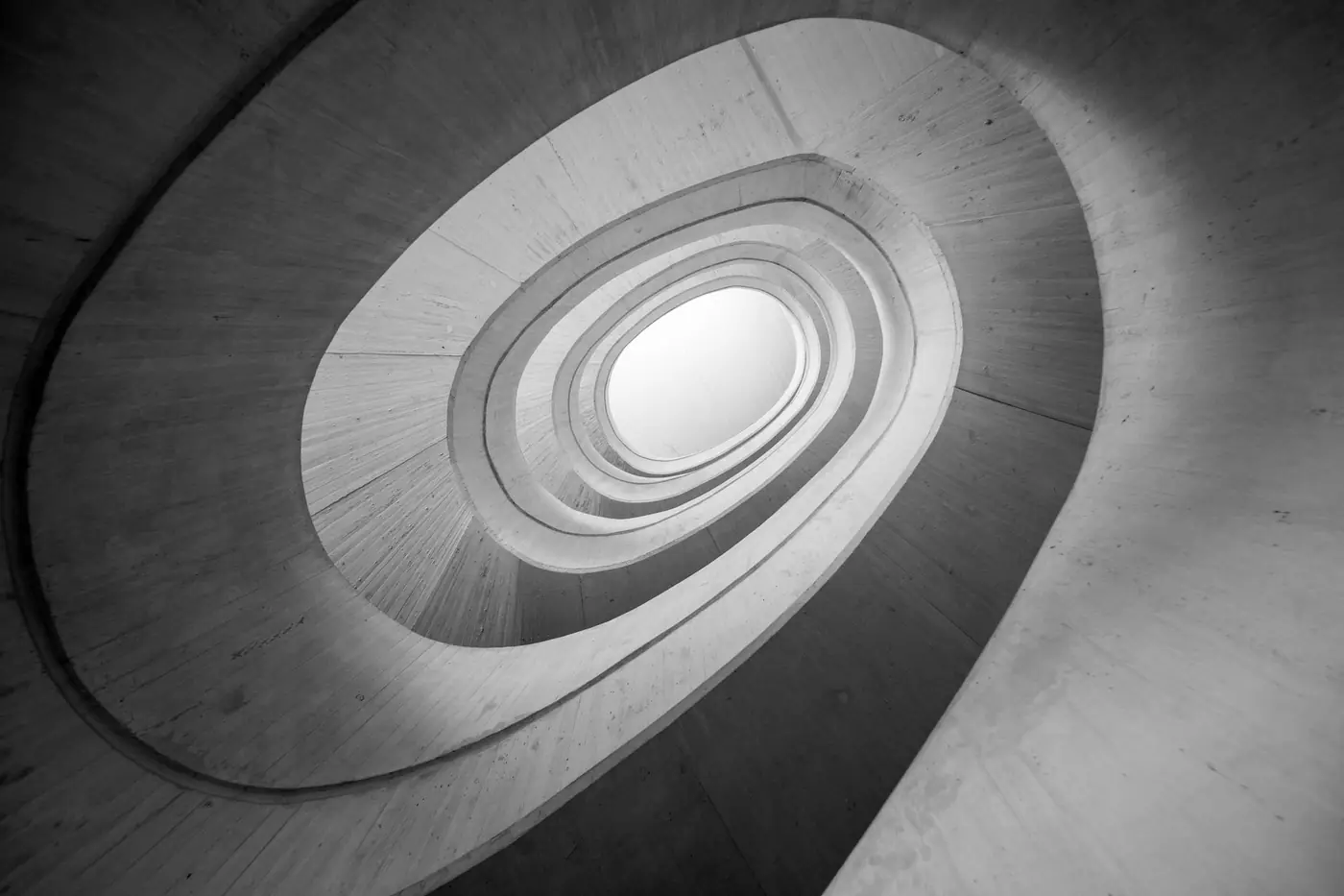 Abstract view of a modern spiral staircase, showcasing geometric curves and light dynamics.